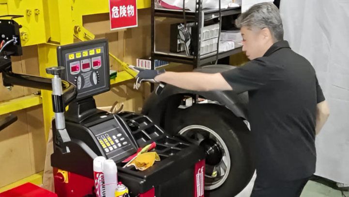 ホイールバランサーで回転するタイヤとホイールを測定している作業風景